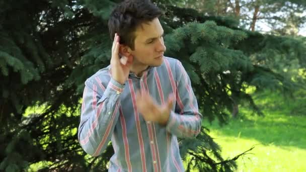 남자가 공원에서 무성한 이어폰과 작용합니다 음악을 즐기거나 통화에 참여하는 것으로 — 비디오