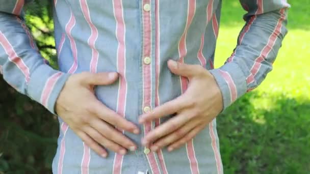 Молодой Человек Полосатой Рубашке Стоит Солнечном Парке Выражая Себя Языком — стоковое видео