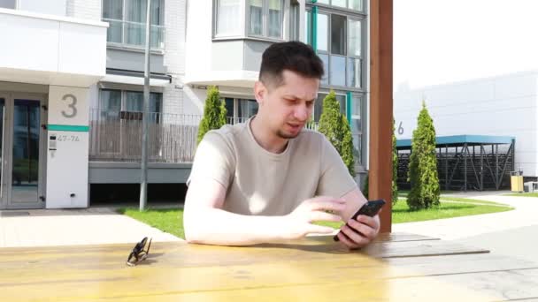 Egy Férfi Egy Asztalnál Mobiljába Merülve Úgy Tűnik Képernyőre Koncentrál — Stock videók