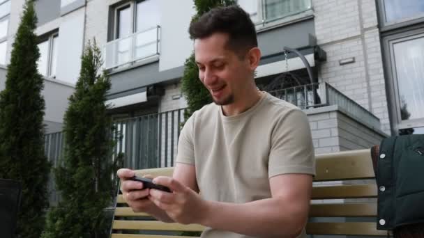 Мужчину Видели Сидящим Скамейке Поглощённым Экраном Своего Мобильного Телефона Кажется — стоковое видео
