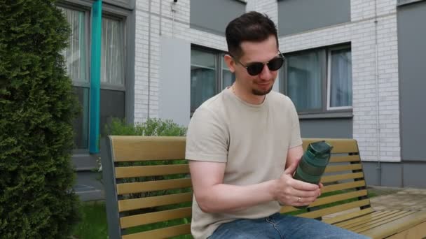 Bir Adam Bankta Oturuyor Elinde Bir Bardak Tutuyor Rahatlamış Görünüyor — Stok video