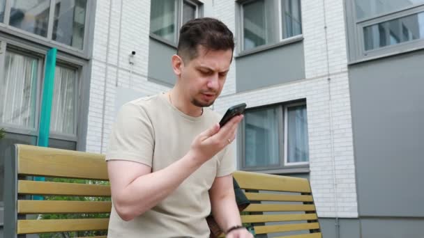 Hombre Visto Sentado Banco Absorto Teléfono Celular Aparece Enfocado Mientras — Vídeo de stock