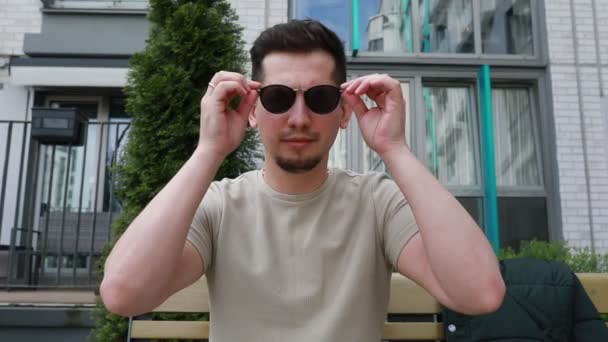 Man Holds Pair Sunglasses His Face Adjusting Them Fit Examines — стокове відео