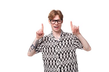 Genç Avrupalı erkek öğrenci, kırmızı saçlı, tişörtlü, eşkenar dörtgen noktalı ellerini reklam alanına koydu..