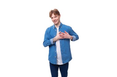 Beyaz stüdyo arka planında mavi kot gömlek giymiş Avrupalı kızıl saçlı bir öğrencinin portresi..