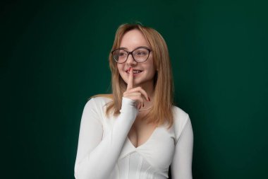 Gözlüklü bir kadın, birinin fotoğrafını çekerken poz veriyor. Kendine güveni tam bir şekilde kameraya gülümsüyor..