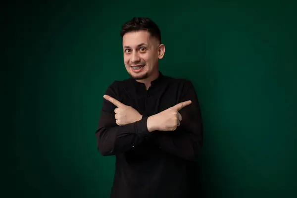 stock image A man wearing a black shirt is pointing at an object or direction, showing emphasis or interest in a specific subject. His gesture suggests urgency or importance in his communication.