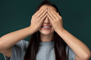 Bir kadın oturuyor ya da ayakta, elleriyle gözlerini kapatıyor. Gözlerini bir şeyden koruyor gibi görünüyor, muhtemelen güneş ışığı ya da parlak bir ışık. Yüz ifadesi bu yüzden görünmüyor.