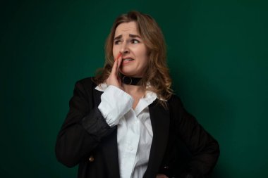 Beyaz gömlek ve siyah ceket giyen bir kadın şehir ortamında güven içinde duruyor. Giysileri profesyonellik ve modern tarz yayıyor, şehir zeminine zıt düşüyor..