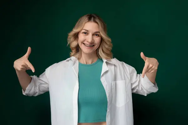 stock image A woman wearing a green top and white jacket stands outdoors. She looks confident and stylish, exuding a sense of sophistication in her attire. The contrast between the green and white colors enhances