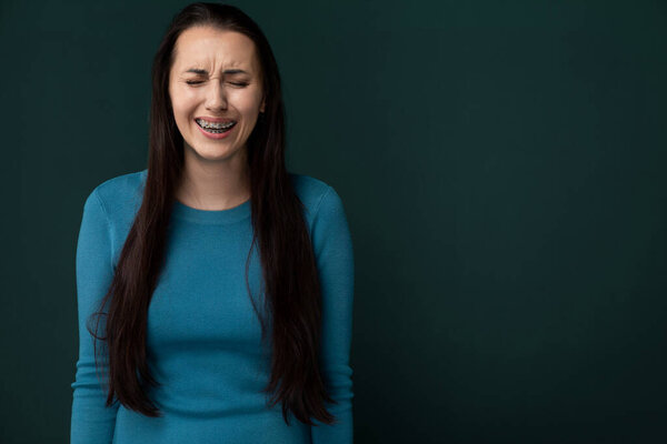 A woman is grinning with her eyes shut in a moment of contentment or joy, showcasing her happiness through a genuine smile that radiates positivity.