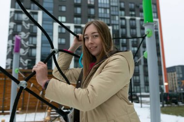 Bir kadın elinde büyük bir nesne tutuyor, güç ve kararlılık gösteriyor. Nesne ağır görünüyor ve sabit kalmak için çaba gerektiriyor..