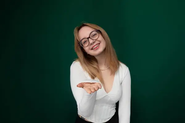 Stock image A woman with glasses pointing at an object off-camera, showcasing a gesture of direction or interest. She appears engaged and focused on the subject of her attention.