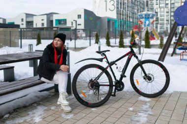 Bir kadın kışın şehir caddesinde yürürken yanında kiralık bir bisiklet götürdü..