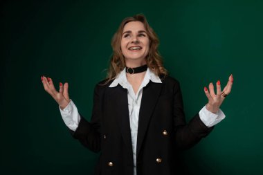 Siyah ceket ve beyaz gömlek giyen bir kadın elleri önünde dışa doğru uzanmış duruyor. Açıklık ya da hazırlık pozisyonunda gibi görünüyor..