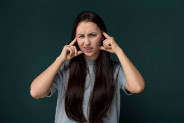 Ayakta duran bir kadın, saçını yüzünün önünde tutuyor, kısmen yüzünü kapatıyor. Düşünceli ya da derin düşüncelere dalmış gibi görünüyor..