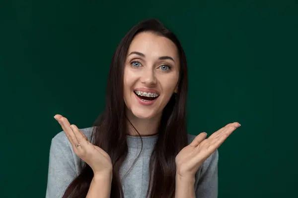 stock image A woman is playfully making a funny face by contorting her features and placing her hands in a comical manner near her face. She is likely expressing humor or jest in this lighthearted moment.