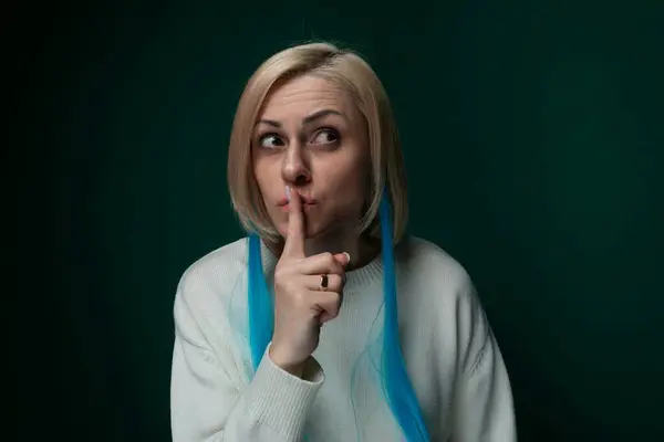 stock image A woman is playfully making a funny face by pulling her cheek with her finger, creating a humorous expression. She is smiling and appears to be in a light-hearted mood.