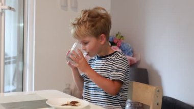 Kafkasyalı genç bir çocuk parlak bir mutfakta masada oturur, küçük bir bardaktan bir içki yudumlar. Önündeki tabakta duran atıştırmalığının tadını çıkarmaya odaklanmış gibi görünüyor. Mutfak özellikleri