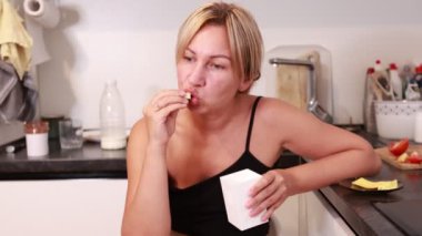 Bir kadın yemeklerinin tadını iyi aydınlatılmış bir mutfakta çıkarıyor. Mutfak becerilerini ve yemeğin tadını çıkarıyor. Yemeğinin tadına baktığında, atmosfer sıcak ve davetkar, onu rahatlatıyor.