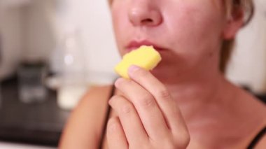 Bir kadın mutfağında taze kesilmiş bir ananasın tadını çıkarıyor. Yemek hazırlarken tatlı tatların tadını çıkarmak için zaman harcıyor. Yemek pişirirken rahat bir an olduğunu gösteriyor..