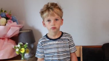 Genç beyaz bir çocuk mutfak masasında oturur, atıştırmalık bir şeyler hazırlar. Parlak ve neşeli bir mutfak ortamı ile çevrili yemeğinin tadını çıkarırken meraklı ve ilgili görünüyor. Taze çiçekler ve...