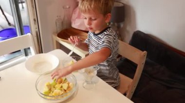Genç bir çocuk hevesle mutfakta taze bir salata hazırlıyor. Bir kaseye renkli malzemeler ekliyor ve onları karıştırıyor, gelişmekte olan aşçılık yeteneklerini gösteriyor. Atmosfer...