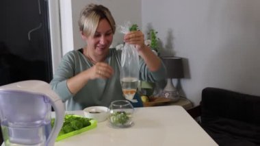 Bir kadın akvaryumunu dikkatlice hazırlar, düzeneği için bitki ve balık seçer. Balıkların iklimine alışma ve su ortamını düzenleme sürecini gösteriyor. Yer aydınlık ve...