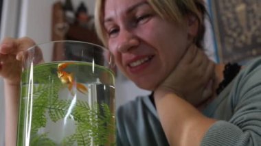 Bir kadın, akvaryumunda yüzen bir Japon balığıyla neşe içinde karşılaşır. Sıcak ve davetkar bir ev ortamında balıkları yakından gözlemler. Sevgi dolu bir bağı yansıtan an
