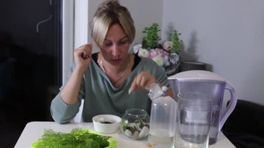Bir kadın evinde bir tatlı su akvaryumu kurmak için dikkatlice hazırlanıyor. Yeni hayatı için canlı ve sağlıklı bir ortam yaratmak için su bitkileri, su ve balık organize eder.