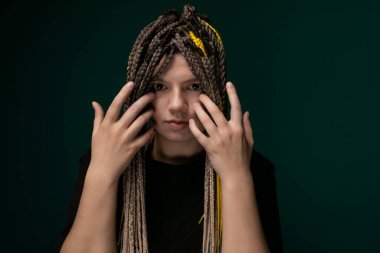 Yüzünü örten, yüzünü gizleyen uzun saçlı bir kadın. Saçları kalın ipliklere düşer, yüzünü çerçevelerken gözlerini ve ağzını kapatır..