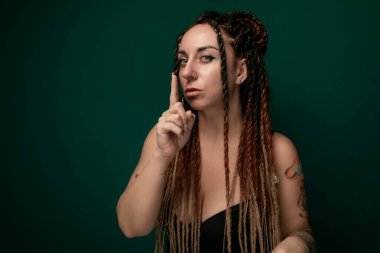 Rasta bukleli bir kadın parmağını burnuna dayayıp derin derin düşünüyor gibi görünüyor. Yüz ifadesi iç gözlem ya da odaklanma olduğunu gösteriyor..