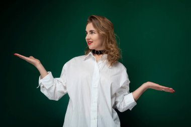 Beyaz gömlekli bir kadın ayakta duruyor ve ellerini uzatıyordu. Elinde bir şey tutuyor ya da yardım istiyor gibi görünüyor. Arkaplan basit ve göze çarpmayan.