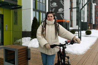 Rasta bukleli bir kadın sokakta bisikletini gezdiriyor. Öylesine geziniyor, gidona tutunuyor ve ilerlerken ileriye bakıyor..