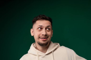 Kapüşonlu bir adam komik bir surat takınıyor, komik bir ifadeyle yüzünü buruşturuyor. Gözleri genişliyor, kaşları kalkıyor ve ağzı oynak bir buruşukluğa dönüşüyor..