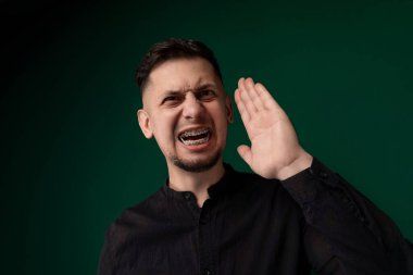 Elleri havada duran bir adam, teslim olma, kutlama ya da heyecan jesti yapıyor. Halka açık bir yerde gibi görünüyor, ya başkaları tarafından çevrili ya da yalnız..