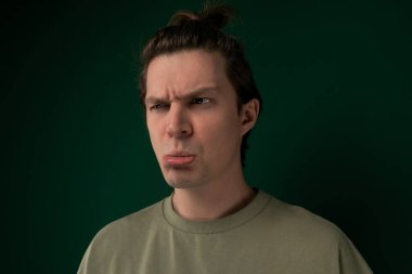 Kafasında dağınık bir topuz şeklinde saç stili olan, saçı kafasının tepesinde gevşek bir topuz gibi toplanmış bir adam. Rahat görünümlü, gelişigüzel bir tarzı var..