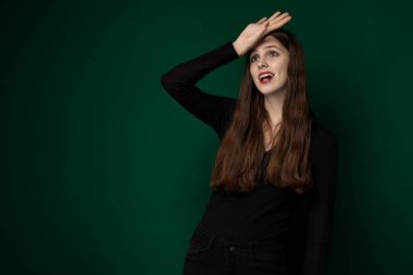 Siyah gömlekli bir kadın fotoğraf çekmek için poz veriyor. Kendine güveni tam bir şekilde kameraya bakıyor ve şık kıyafetini gösteriyor..