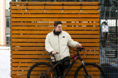 Kışlık ceketli genç bir Avrupalı bisikletini dışarı çıkardı..