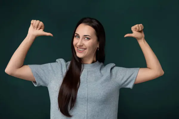 stock image A woman with long brown hair is standing with her arms lifted high above her head in a gesture of celebration or triumph. Her hair flows down her back as she stands with a confident posture.