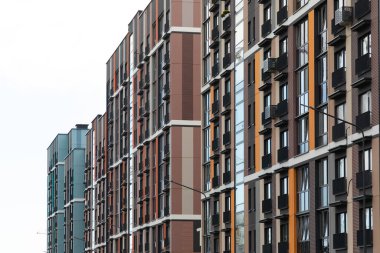 Bir yerleşim bölgesinde büyük apartmanlar göze çarpıyor. Çeşitli mimari tarzları, kira ve ipotek seçenekleriyle çağdaş kentsel yaşamı vurguluyor.