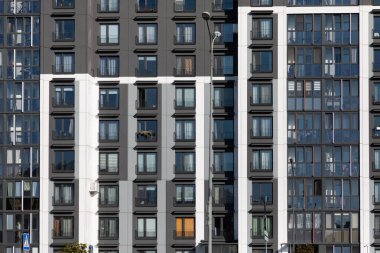 Manzarada, kentsel gelişmeler arasında yaşayan çağdaş tasarım ve cemaatin vurgulandığı yoğun bir yerleşim alanındaki yüksek katlı apartmanlar yer alıyor..