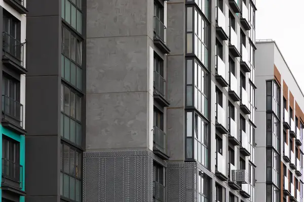 Yüksek katlı apartmanlar hareketli bir yerleşim bölgesinde uzun süre ayakta kalarak, kentsel yaşamın özünü ve modern konut talebini vurguluyor. Özellikler arasında balkonlar ve çeşitli tasarımlar yer alıyor.