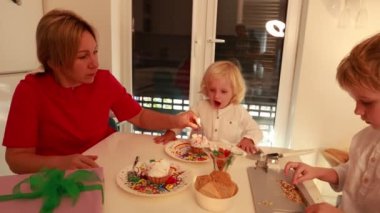 Aile, anne ve oğlunun doğum günü kutlaması için sıcak ve şenlikli bir ortam yaratmak için mum yaktıkları lezzetli ikramlarla dolu bir masanın etrafında toplanır..