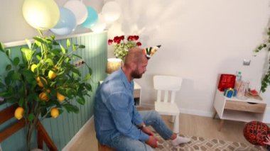 Bir baba ve oğlu, sevgi ve kahkaha dolu neşeli bir atmosfer ve renkli süslemelerle çevrili bir şekilde evde çocuk doğumgününü kutluyorlar..