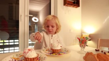 Sıcak bir yuva ortamında, bir anne ve iki oğlu doğum gününü neşeyle kutluyorlar. Çocuklar süslemelerle çevrili çöreklerle mutlu mesut eğleniyorlar..