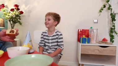Bir baba ve küçük oğlu, pasta, renkli süslemeler ve birlikte neşeli anlarla dolu evde özel bir doğum günü kutlamasının tadını çıkarıyorlar. Atmosfer sıcak ve neşeli..