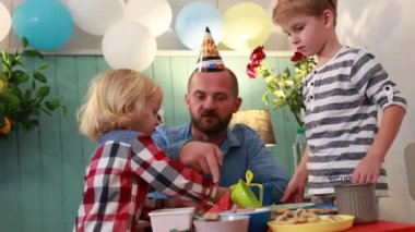 Bir baba ve oğlu renkli süslemeler, pasta ve hediyelerle dolu evde neşeli bir doğum günü kutlaması yapıyorlar. Neşeleri ve bağları bu özel anda parlıyor..