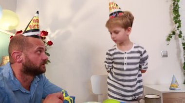 Bir baba ve oğlu, pasta, parti şapkaları, kahkahalar ve aralarında paylaşılan unutulmaz anlarla dolu evde özel bir doğum günü kutlaması yapıyorlar..