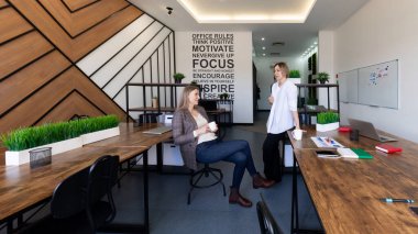 Meslektaşlar çağdaş bir ofis ortamında verimli bir tartışmaya girişirler. Parlak odada bitkiler ve motivasyon kaynaklı alıntılar yer alıyor ve işbirlikçi atmosferi artırıyor..